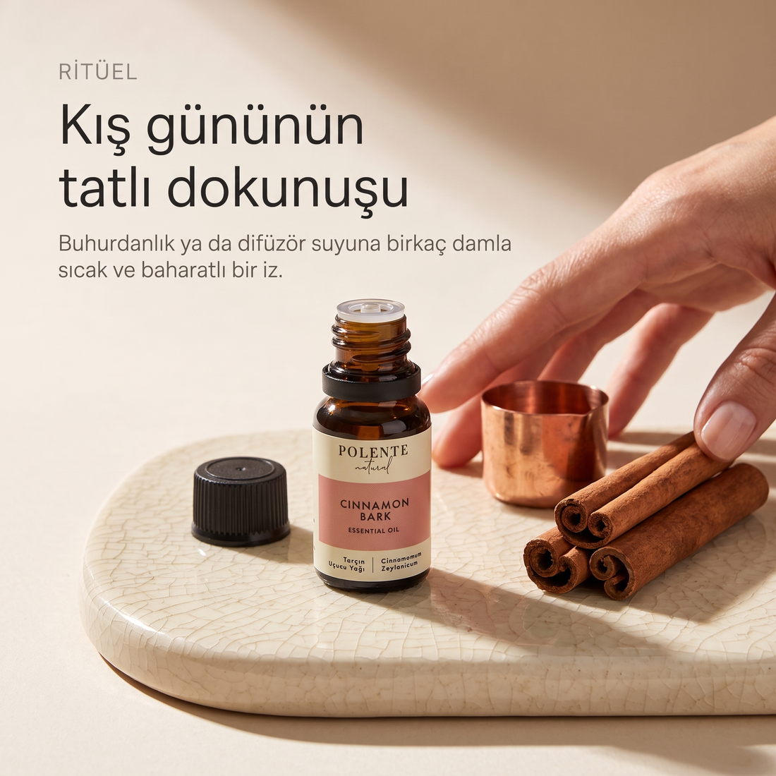 Tarçın Uçucu Yağı 10 ml — krem seramik levha üzerinde ritüel kurulumu; kış gününün sıcak dokunuşu