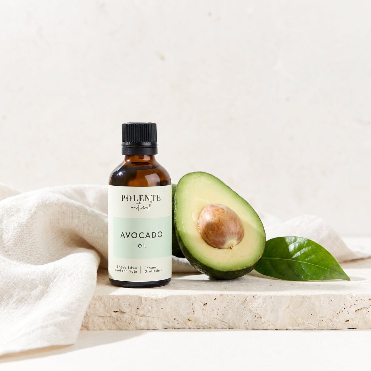 Avokado Yağı Soğuk Sıkım 50 ml — ikiye bölünmüş avokado ve yaprağıyla botanik konsept görseli